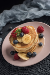 Delicious american pancakes with berries, banana and syrup. Vertical. Copyspace