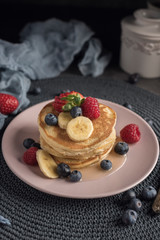 Delicious american pancakes with berries, banana and syrup. Vertical. Copyspace