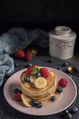 Delicious american pancakes with berries, banana and syrup. Vertical. Copyspace