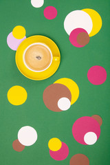 Cup of Coffee and colorful paper circles on green paper background