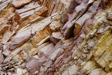 Layers of mountain rock, painted in different shades of yellow and pink.