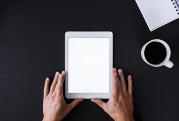 A top view of male hands holding tablet on a desk. Copy space.