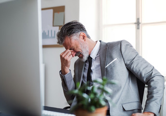 A frustrated businessman sitting at the desk in an office, hearing bad news.