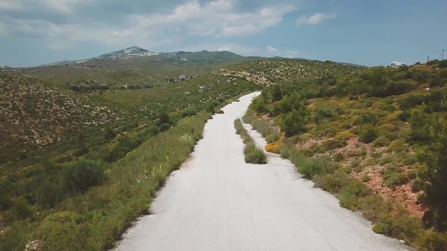 Forward drone shot over a motorcyclist riding towards and passing under the camera during a summer afternoon. 4k drone quality