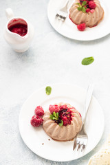 Two mini chocolate cheesecake with raspberry sauce and mint. No crust cheesecake. Diet dessert. Light grey stone concrete background. Copy space.