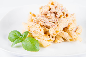 Pasta - penne with white cream sauce with bacon on a plate, decorated with fresh basil