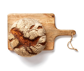 Freshly baked bread on wooden cutting board isolated, top view.