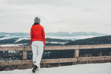 A young tourist girl admires the wonderful landscape of the winter Carpathian mountains