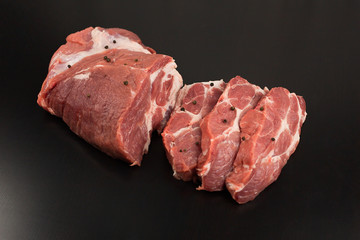 Fresh pork steaks on black wooden background