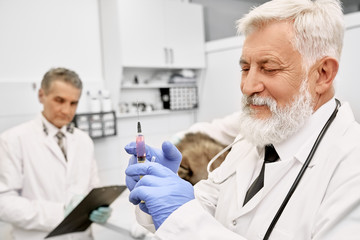 Elderly vet doctor holding needle for injection.