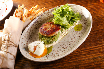 Pashto egg with cutlet and salad on plate and black wood background 