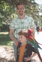 Portrait of father and son with macaw parrot