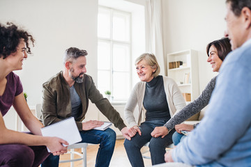 Men and women sitting in a circle and holding hands during group therapy.