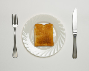 SLICE OF TOAST ON WHITE PLATE WITH KNIFE AND FORK