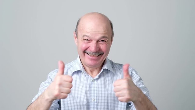 Handsome senior man shows thumb up