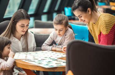 Happy young women with children sitting at table in restaurant