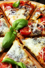 Vegetarian Italian pizza with melted cheese, red tomatoes and green basil on a table decorated by cheese, tomato and cherry tomatoes