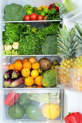 Opened fridge full of fresh colorful fruits and vegetables