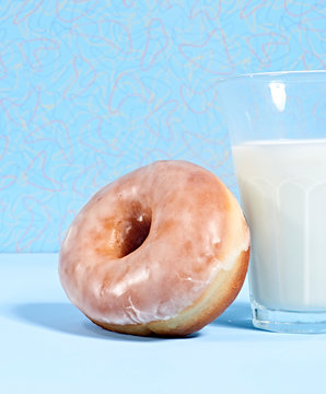 Glazed donut leaning against glass of milk
