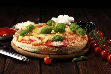 Delicious pizza with pineapple, ham slice, bacon slice, mozzarella cheese, pizza sauce on rustic background for fast food and ready to eat concept