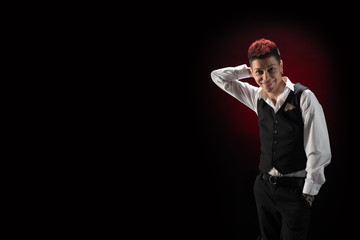 Woman with red hair in a black suit and white shirt posing on a black background