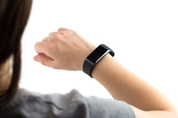 Fitness bracelet on a female hand. The girl looks at the display of a fitness tracker. View from over the shoulder.
