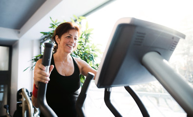 A cheerful female senior in gym doing cardio workout.