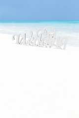 decorative word WEDDING on sandy beach