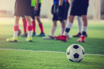 Obraz na płótnie Canvas soccer ball on green artificial turf with blurry soccer players standing