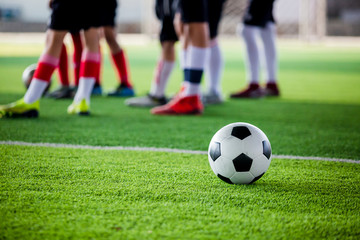 Obraz na płótnie Canvas soccer ball on green artificial turf with blurry soccer players standing