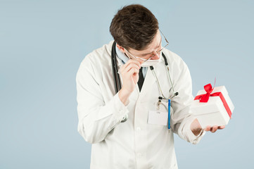 doctor student with a gift in his hands on an isolated blue background.concept medicine and health, holidays and gifts