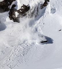 Fototapeta na wymiar Freerider snowboarder jumping off a cliff and moves down the slope of the mountains