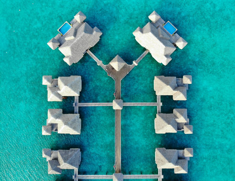 Aerial view of overwater bungalow villas with thatched roofs in the Bora Bora lagoon in French Polynesia