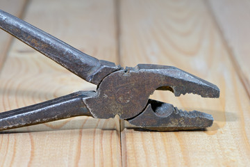 Old rusty pliers on wooden background. Close up