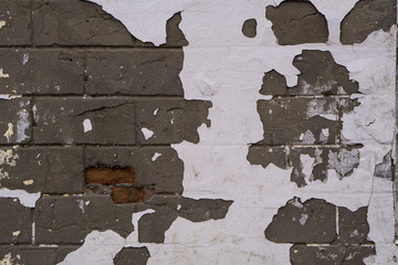Background of old vintage dirty brick wall with peeling plaster, texture.Brick white, brown. Peeled paint on a brick wall.