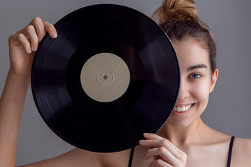 Beautiful girl portrait, holding an LP microgroove vinyl record on bright background