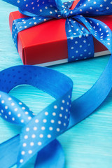 Close up of red gift box with spotted blue bow and long ribbon