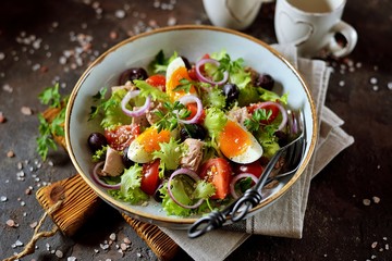 Healthy organic lettuce salad with canned tuna, cherry tomatoes, sun-dried olives, red onion, egg and parmesan. Top view. Copy space. 