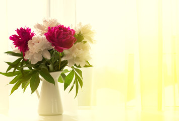 White and pink peonies in vase on white table