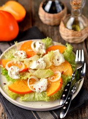 Persimmon salad with lettuce, sweet onions, soft cheese, parmesan, pink pepper, lemon juice and olive oil.