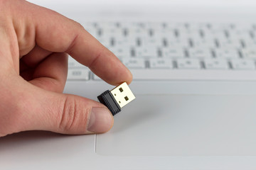 mini flash drive in hand on laptop keyboard background closeup