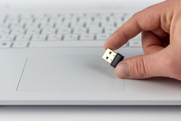 mini flash drive in hand on laptop keyboard background
