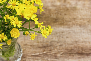 yellow flowers in vase on wooden background top view, beautiful background