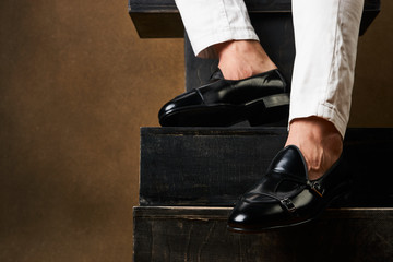 Businessmans foot wearing black leather shoes and white jeans, close-up