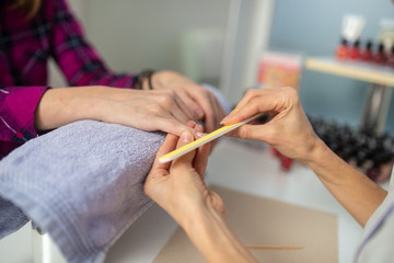 Closeup of professional cosmetologist filing finger nails
