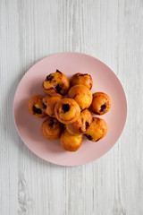 From above, homemade muffins with cherry on pink plate over white wooden table. Flat lay, overhead, top view