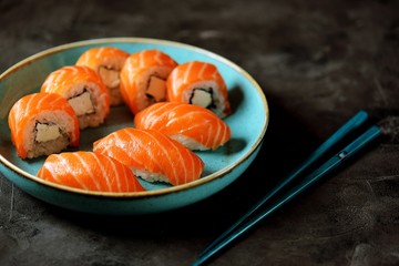 Philadelphia homemade sushi rolls in a blue plate on a black background.