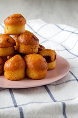 Homemade mini muffins with cherry on pink plate, side view. Closeup.