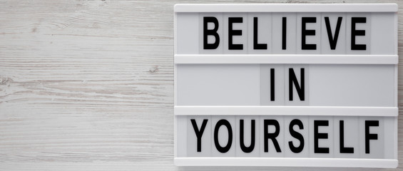 'Believe in yourself' words on modern board on a white wooden surface, top view. From above, flat lay, overhead. Space for text.