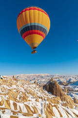 colorful balloon over the extraordinary rocks formations rock hills on snowy winter of Cappadocia, Nevsehir,